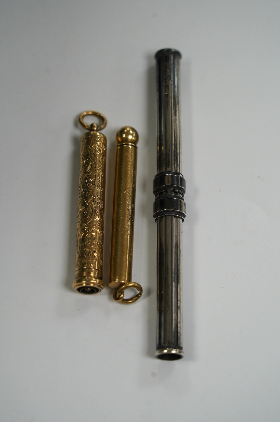 Two yellow metal overlaid propelling pencils, including late Victorian with engraved inscription, 54mm and one other silver cased propelling pencil and pen combination, 10cm long when closed. Condition - fair